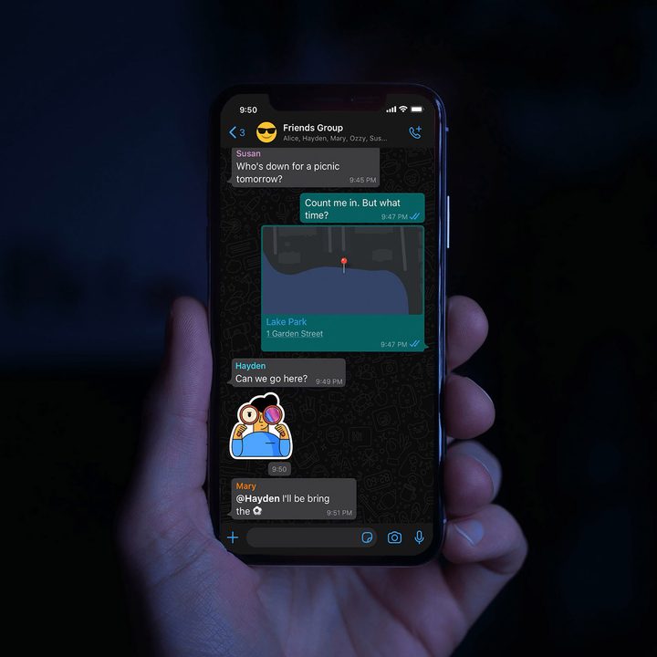 Person holding an iPhone with the WhatsApp messenger app opened.
