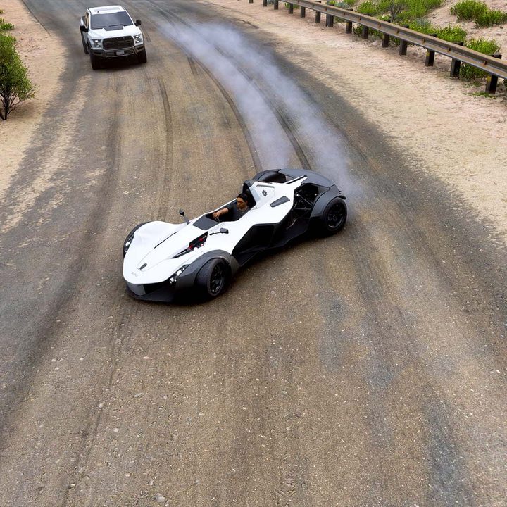 The front view of a white car driftng around traffic.