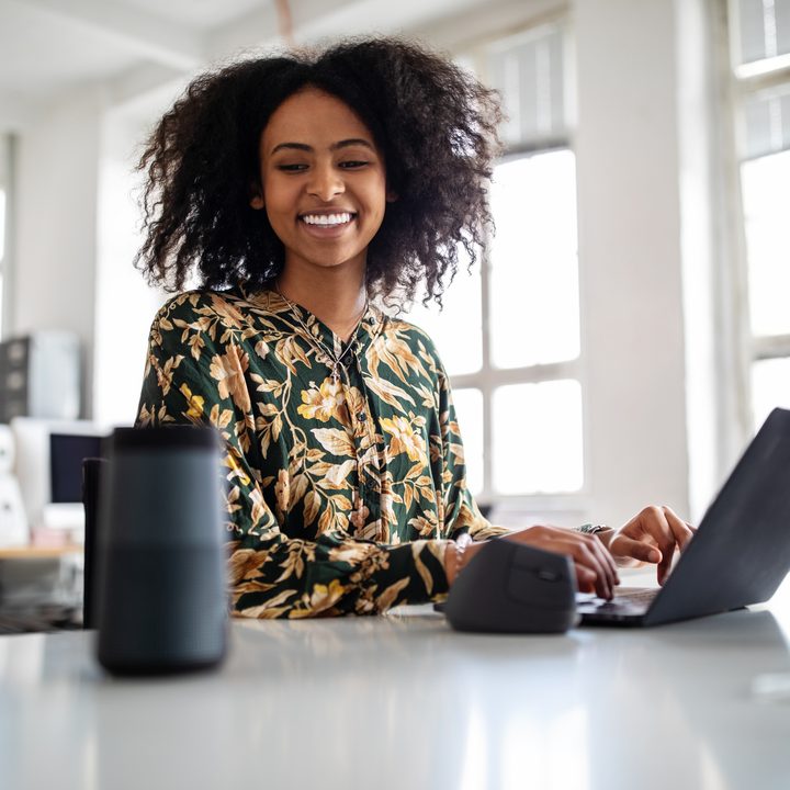 Woman using smart speaker while working in office.
