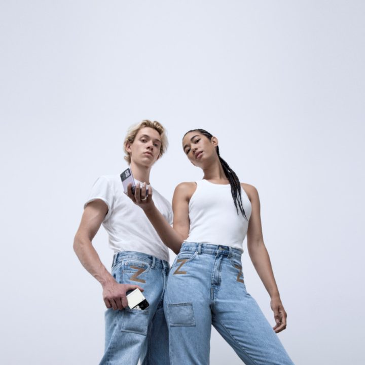 Two people hold a Galaxy Z Fliup 3 which wearing jeans designed for the phone.