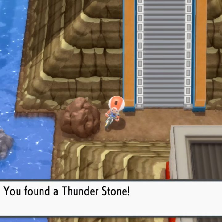 A trainer stopping his bike near a rock.