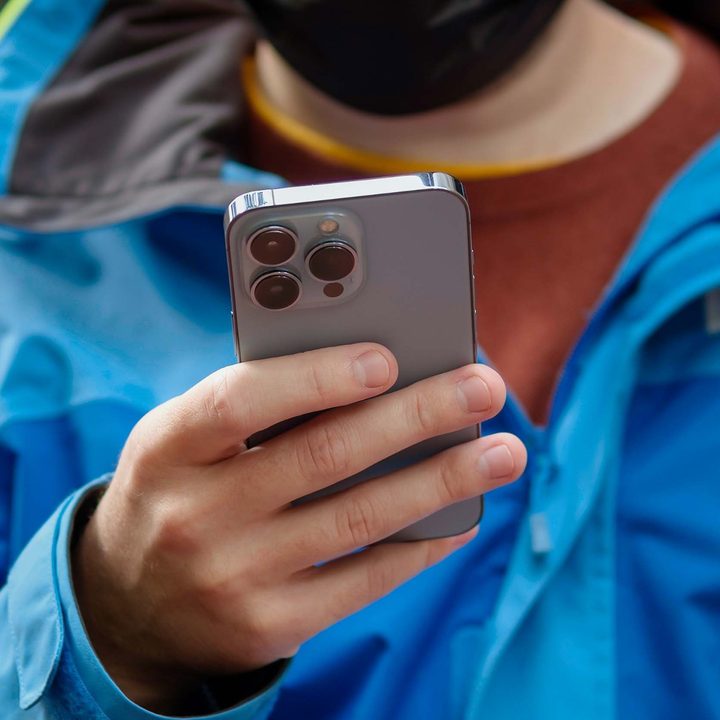 Man holding the iPhone 13 Pro showing its rear panel.