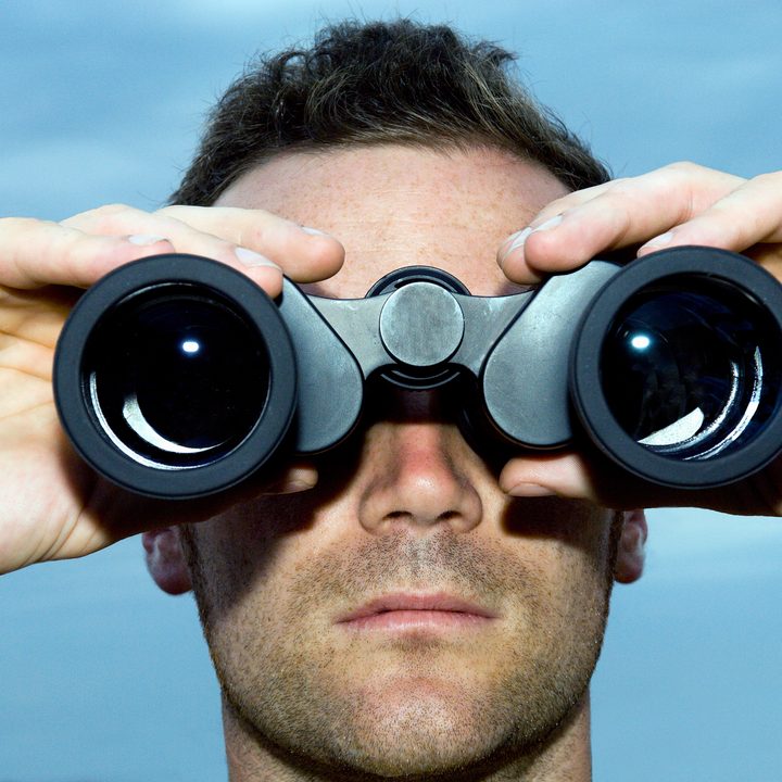 Man holding binoculars up to his face.