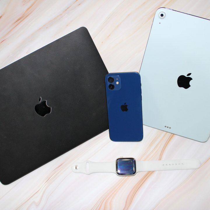 A MacBook Air, iPhone 12, iPad Air and Apple Watch SE on a table.