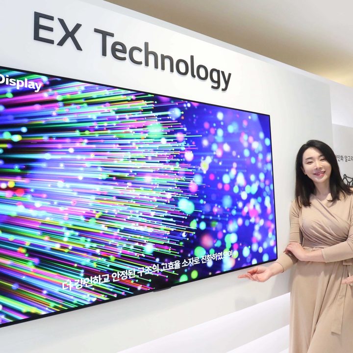 Models stand beside a demo of LG Display's OLED EX panel.
