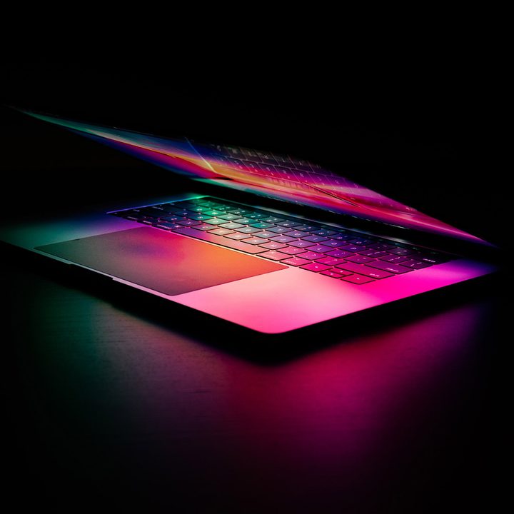 A Macbook Pro sits in the dark, illuminated by its own screen.