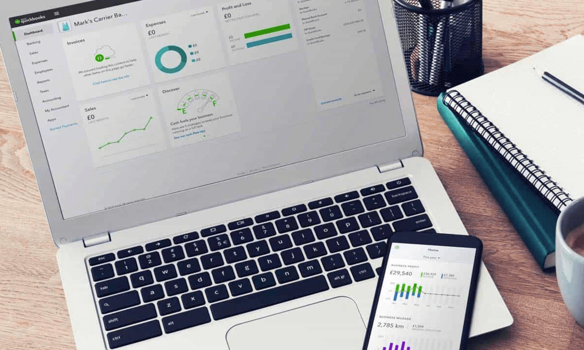 A laptop sits open with Quickbooks software running on the screen.