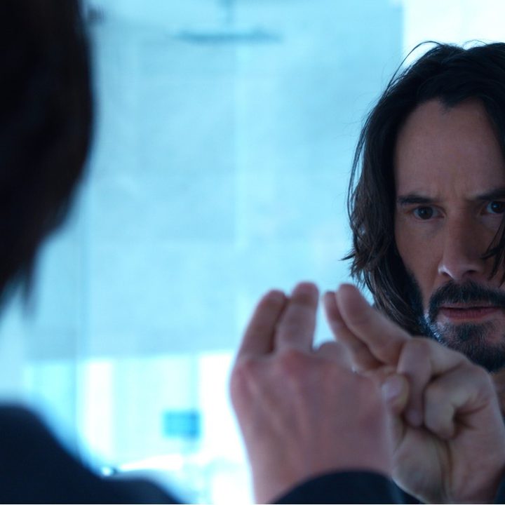 Keanu Reeves taps a mirror in a scene from The Matrix Resurrections.