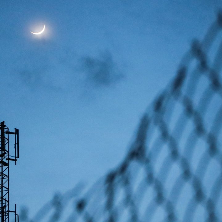 A cellular radio tower in the moonlight.