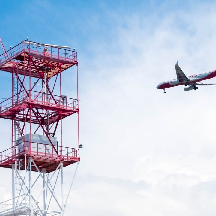 Passenger airlines flying past a large radio communications tower.