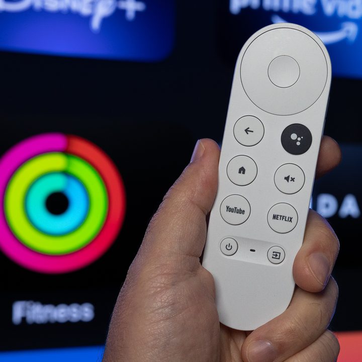 The Google TV remote in front of Apple TV Fitness.