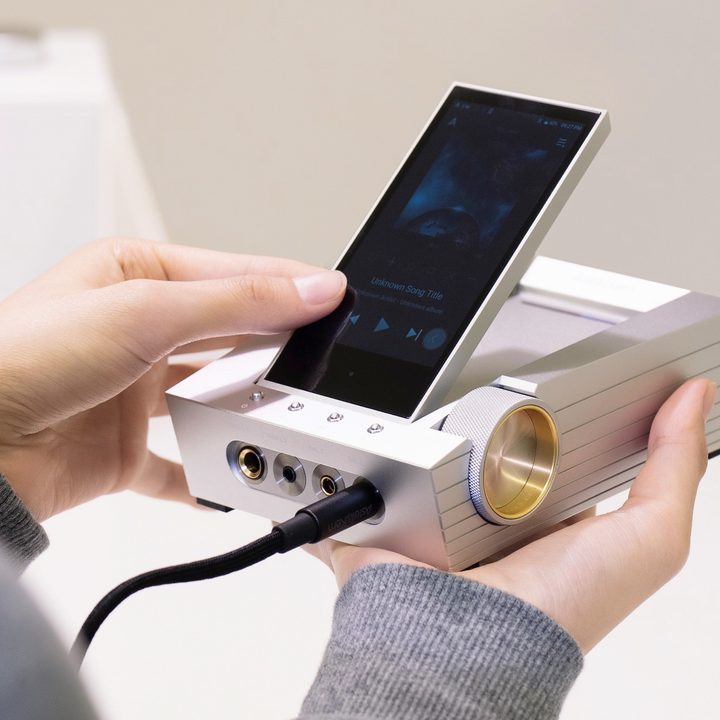 Astell&Kern Arco CA1000 headphone amp and digital audio player held in someone's hand.