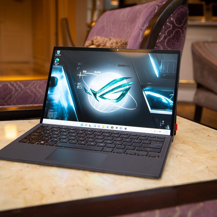 Asus ROG Flow Z13 gaming laptop sits open on a side table in a living room.
