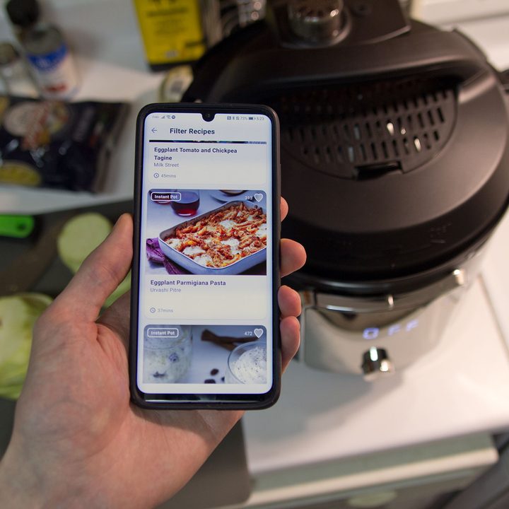 Instant Pot app running on a smartphone with an Instant Pot and ingredients in the background.