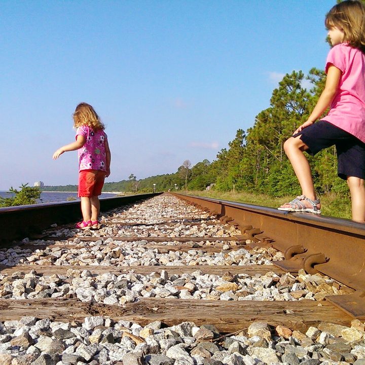 Girls walking on train tracks.
