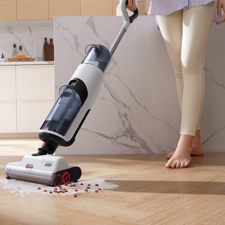 A Roborock Dyad cleans up spilled cereal on a hardwood floor.