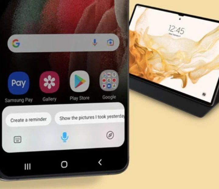 A Samsung Galaxy phone showing off Bixby with a tablet in the background.