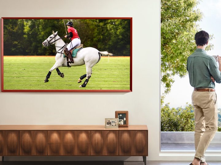 A Samsung The Frame TV displaying a person riding a horse playing polo.