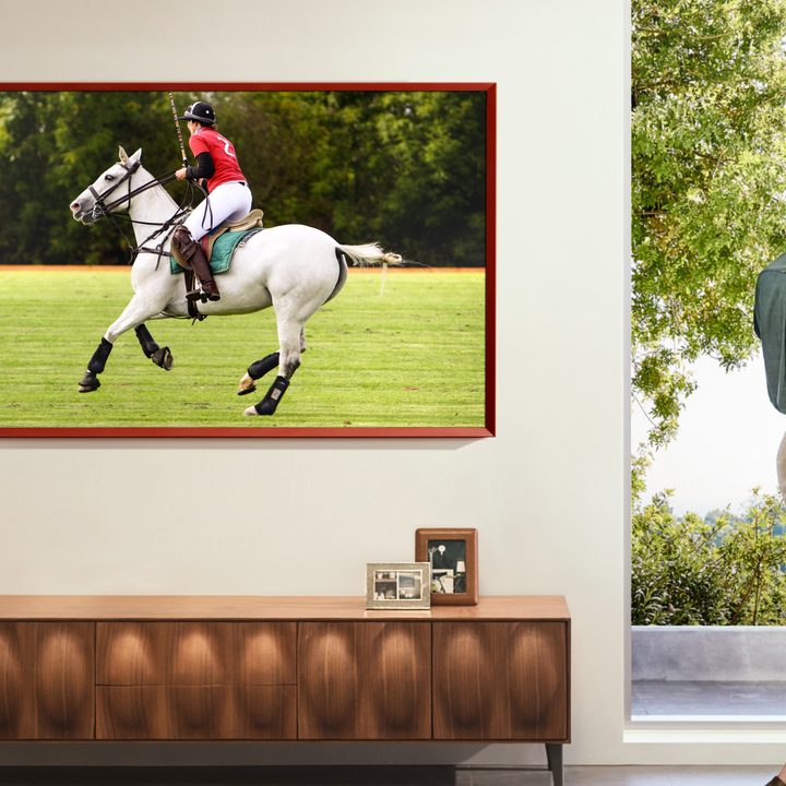 A Samsung The Frame TV displaying a person riding a horse playing polo.