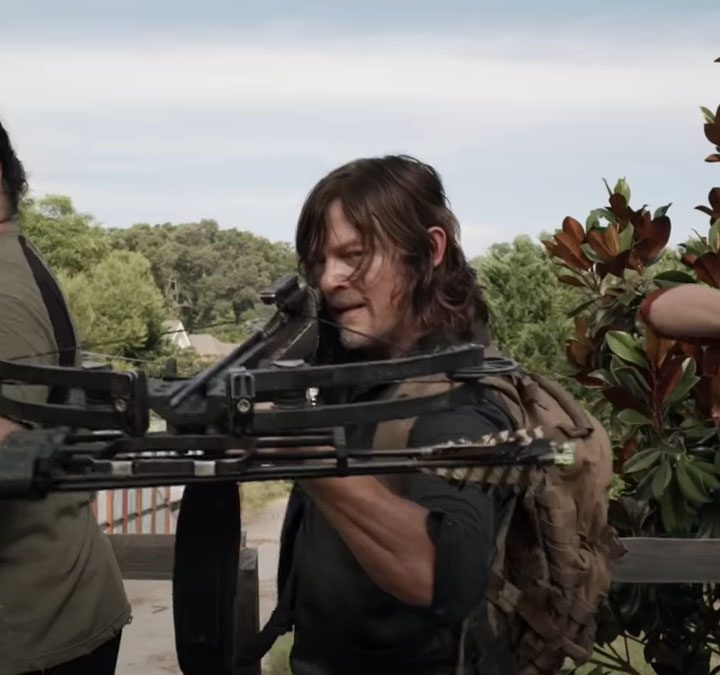 Three castmembers of The Walking Dead with weapons drawn.
