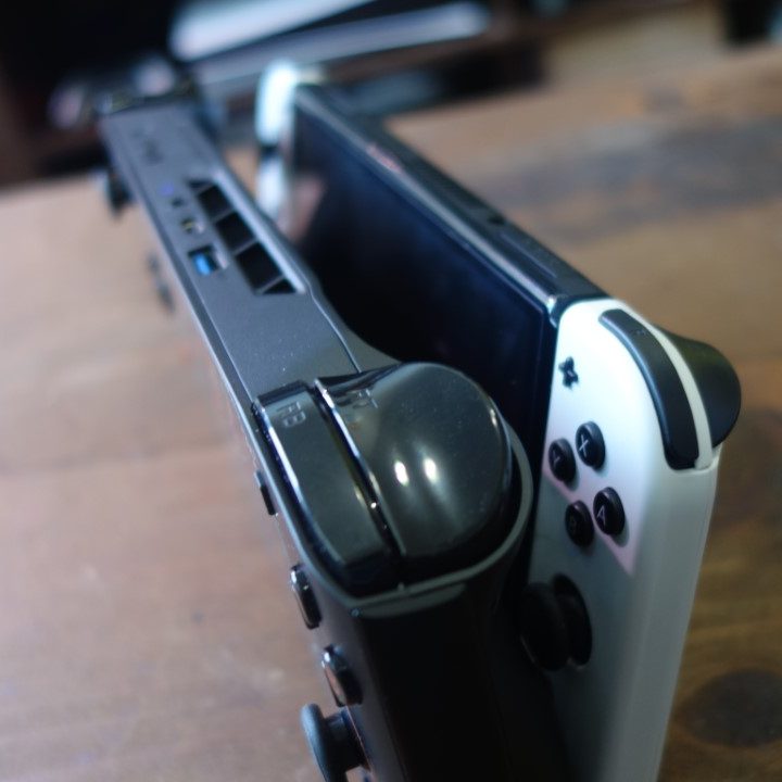 A Onexplayer Mini stands next to a Nintendo Switch OLED.