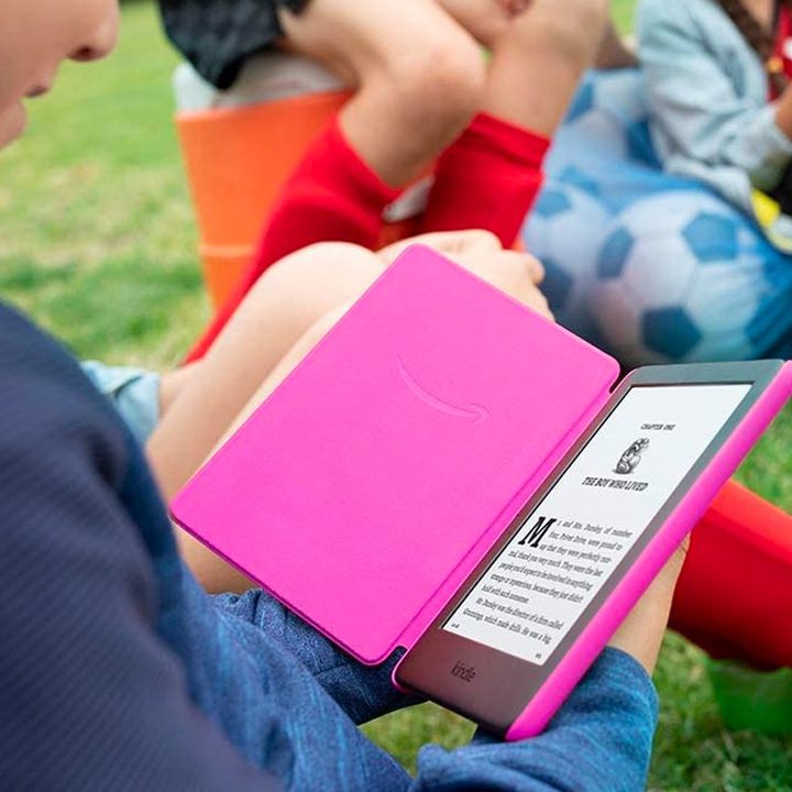 A child reads outside on the Amazon Kindle Kids Edition.