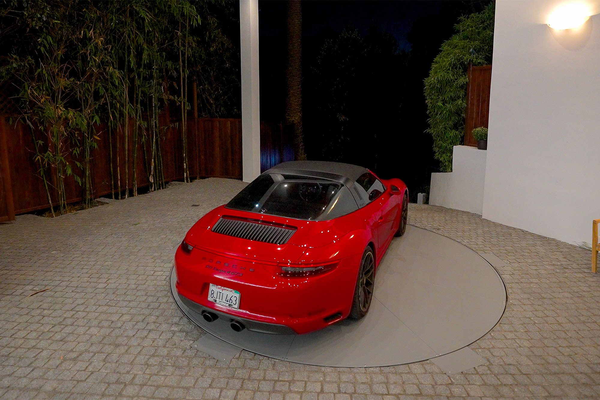 A red sports car turns on a turntable in a driveway.