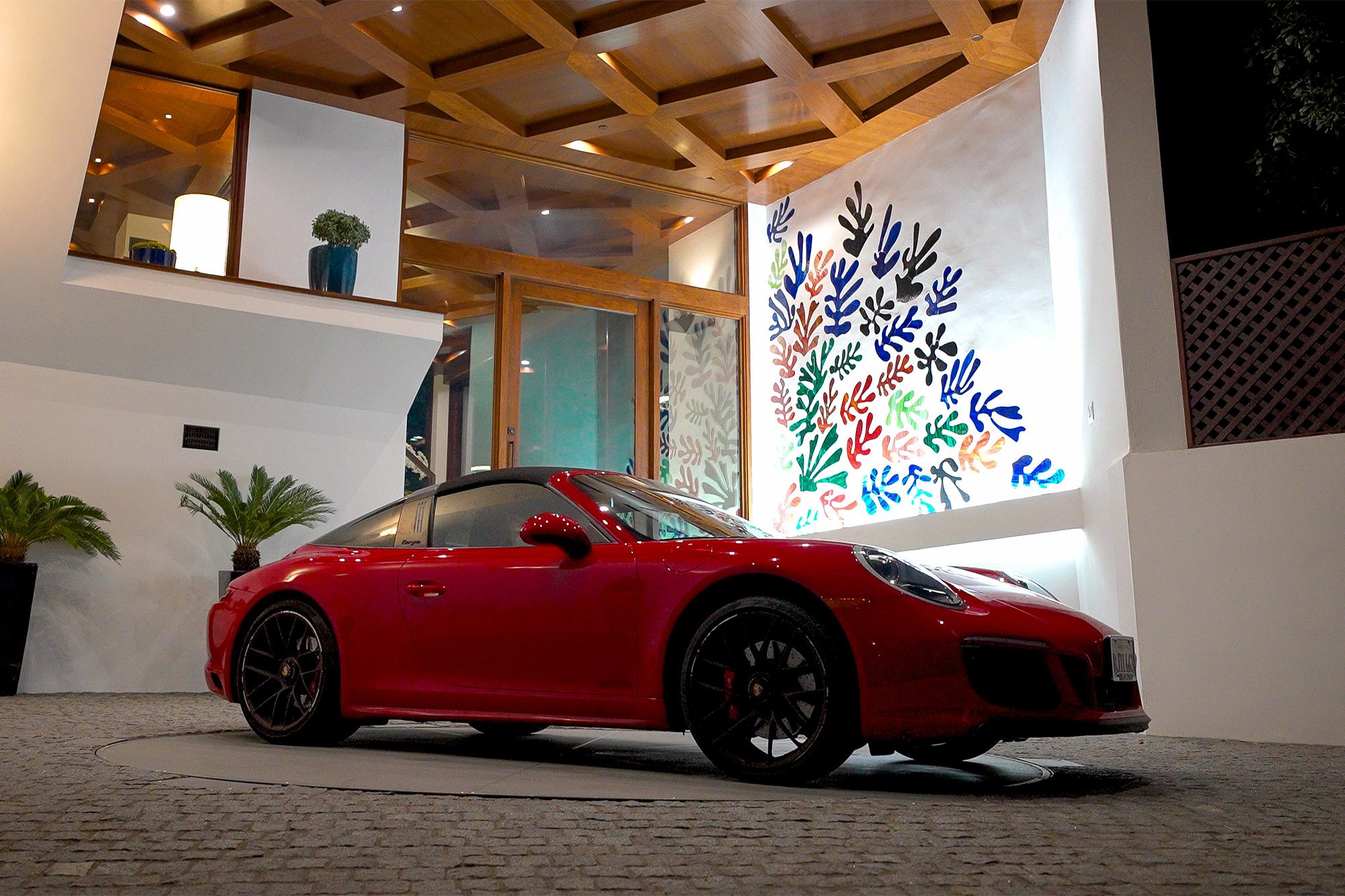 A red sports car turns on a turntable in a driveway.