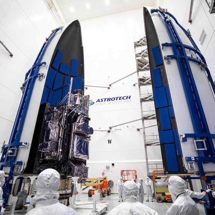 A NOAA weather satellite being placed inside a rocket fairing ahead of launch.