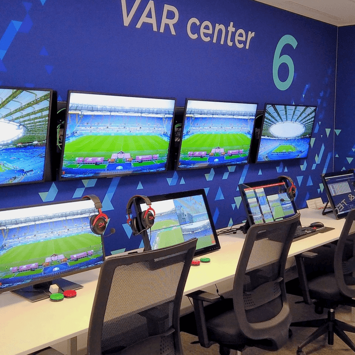 Hawk-Eye control room with four wall-mounted TVs and four compute review stations with headphones.