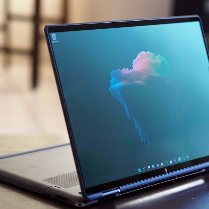 The HP Spectre x360 16 sits on a desk with it's keyboard folded under, allowing it to stand.