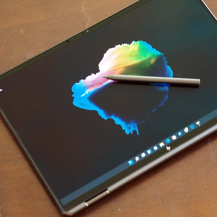 The HP Spectre x360 16 is seen laying in tablet mode with a stylus sat on top of the screen.