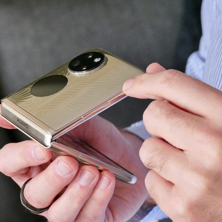 A man holds a half-closed Huawei P50 Pocket.
