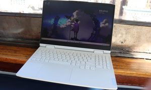 The white 15-inch IdeaPad Gaming 3 is placed on a seating area near a large window.