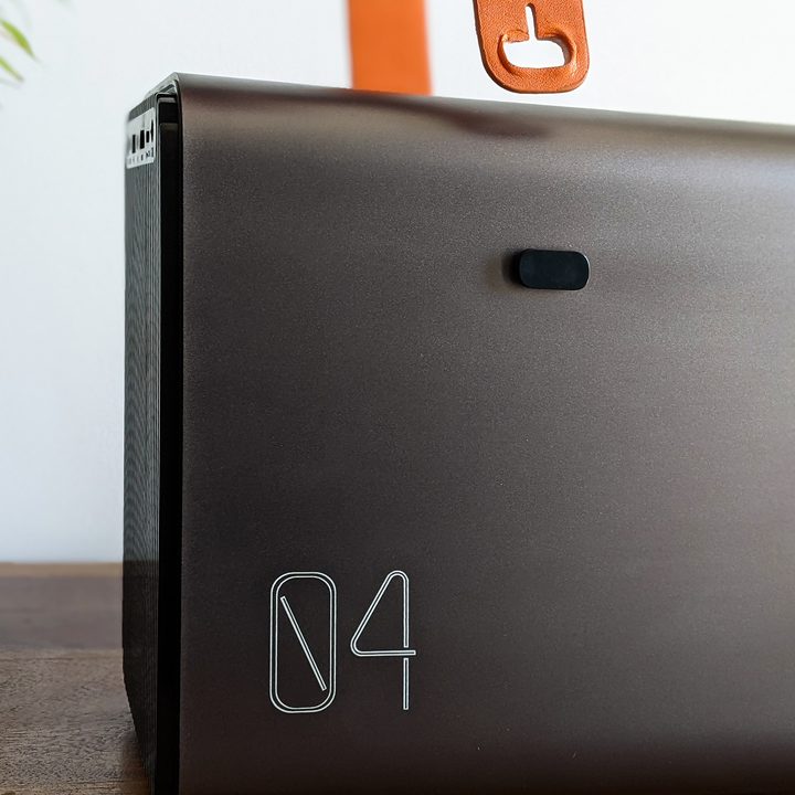 The Jireno Cube 4 portable 1080p projector has a side buckle for its orange leather strap.