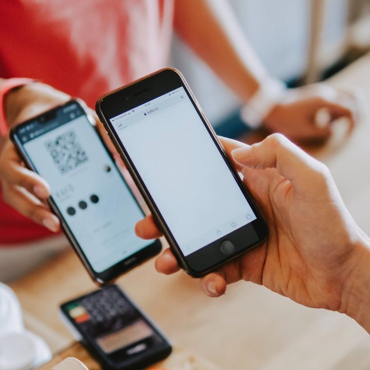 A person holds a smartphone over another smartphone at a retail counter.