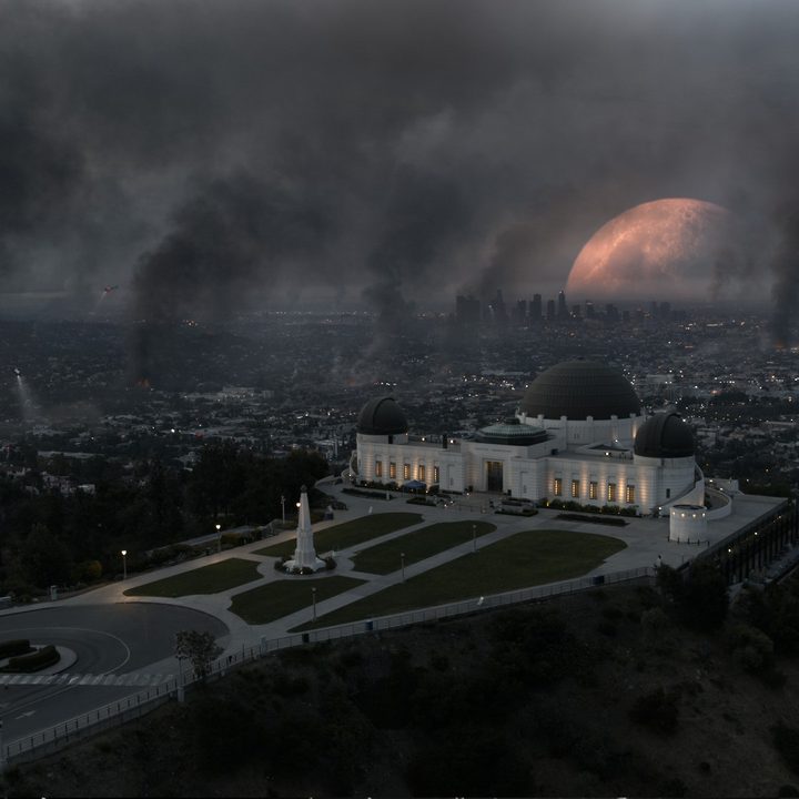 The moon rises too close to Earrth in the backdrop of a smoldering landscape in Moonfall.