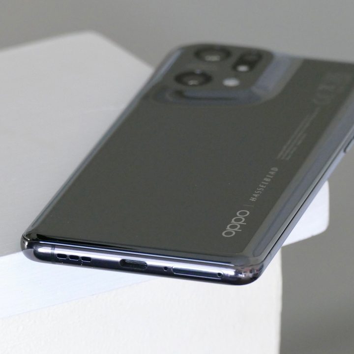 The Oppo Find X5 Pro on the edge of a table with the charger port visible.