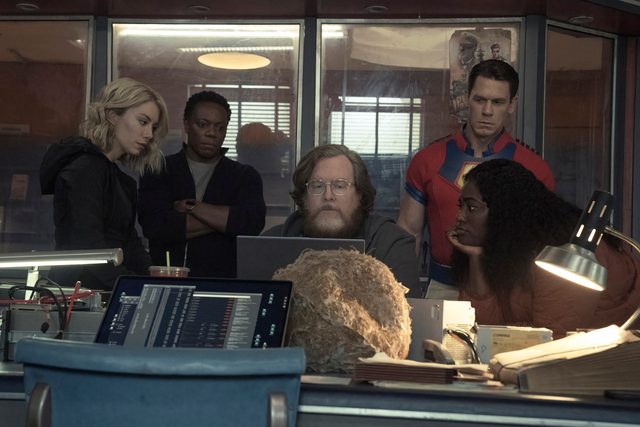 The cast of Peacemaker gathers around a computer.