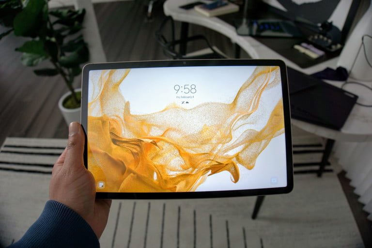 The Samsung Galaxy Tab S8 being held up with the lock screen showing.