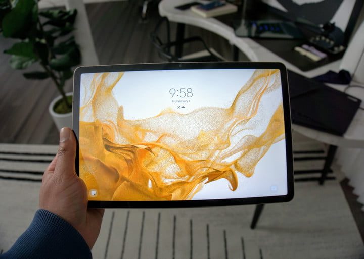 The Samsung Galaxy Tab S8 being held up with the lock screen showing.