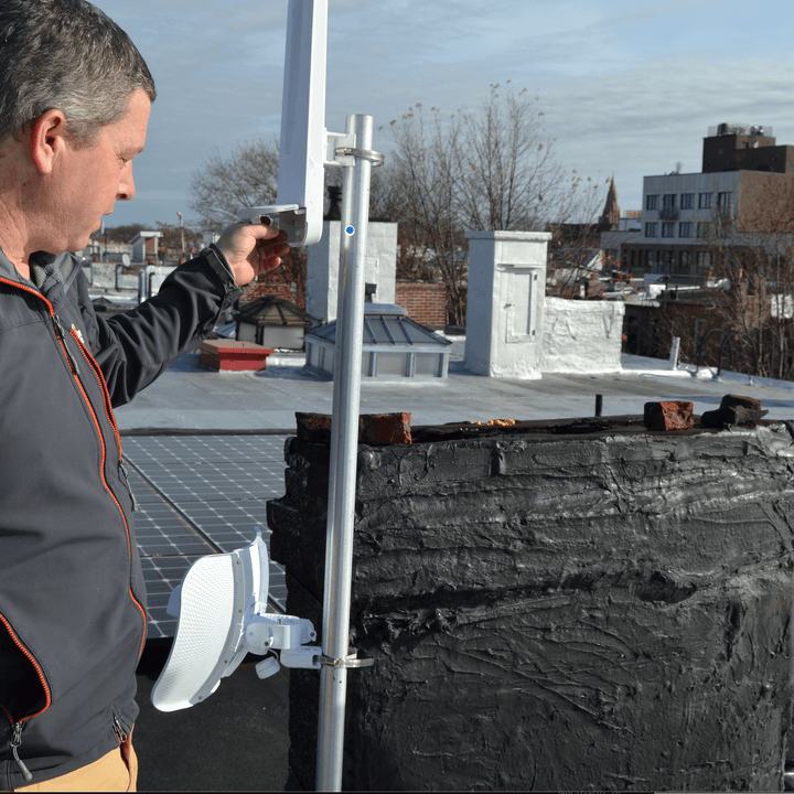 An NYC Mesh volunteer installs networking gear on a rooftop.