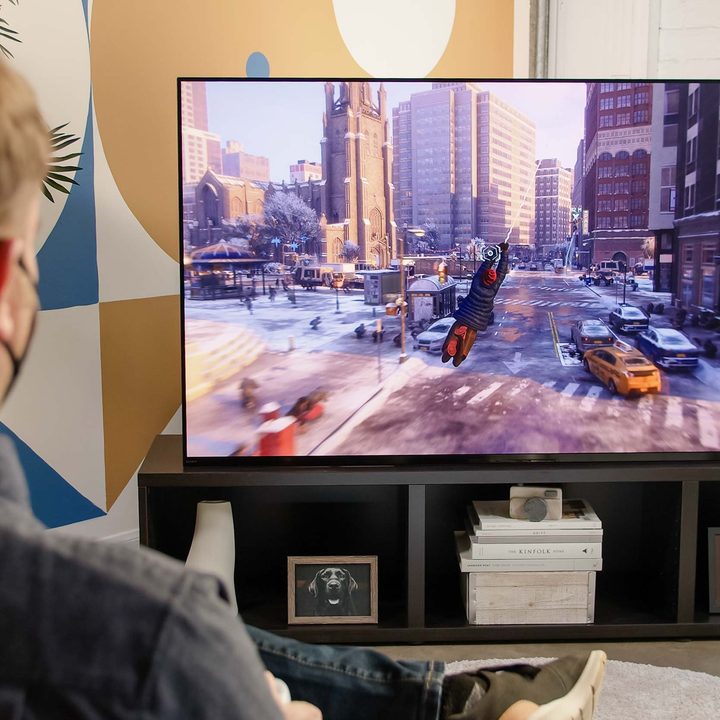 Caleb Denison sits in front of the Sony A95K TV playing Marvel's Spider-Man: Miles Morales on the PS5.