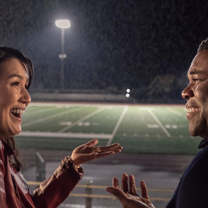 Zoe (Zoe Chao) and Aniq (Sam Richardson) laugh together on the bleachers in The Afterparty on Apple TV+.
