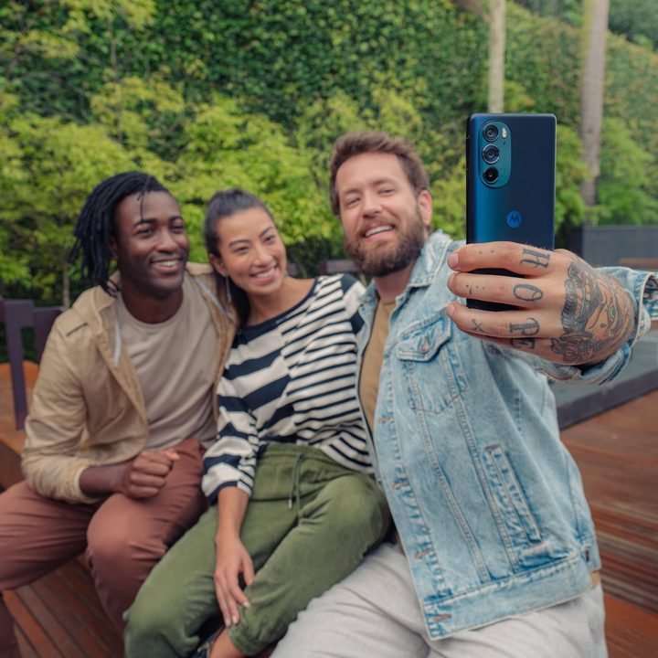 A man takes a selfie with friends using a Motorola Edge Plus 2022 smartphone.