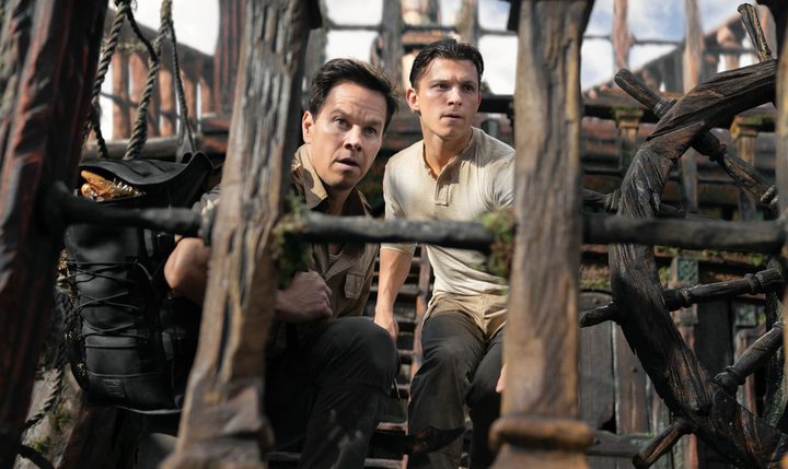 Tom Holland and Mark Wahlberg sit on a pirate ship in Uncharted.