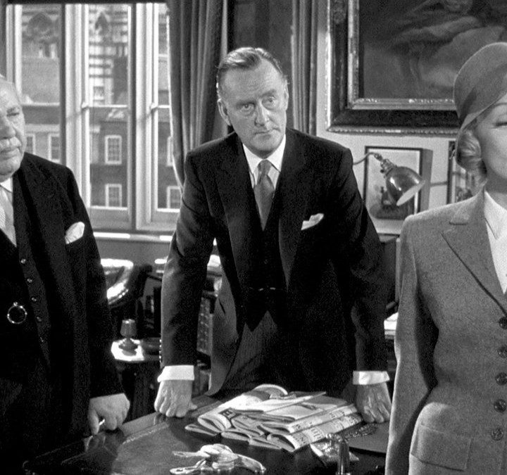 A woman stands in front of two men in Witness for the Prosecution.