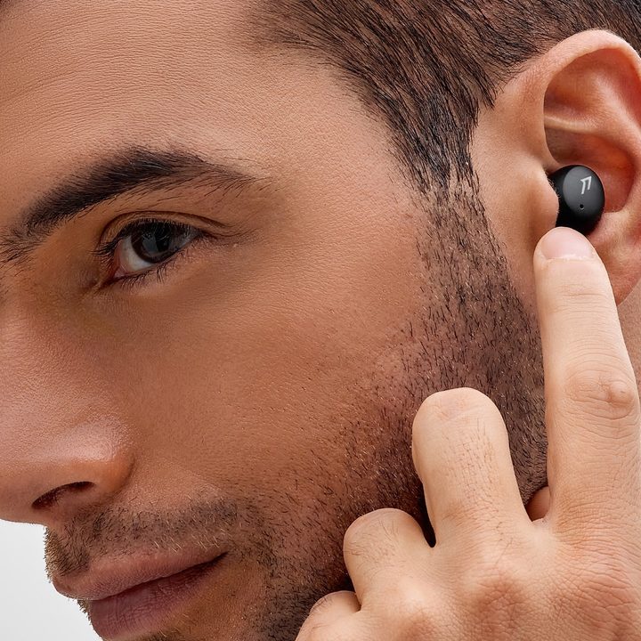 A man wears the 1More ComfoBuds Mini wireless earbuds.