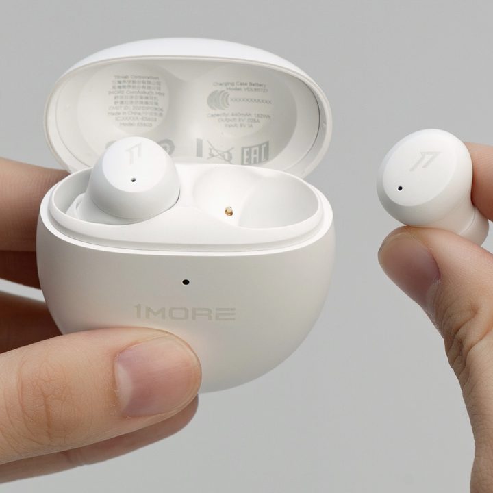 Hands seen holding 1More ComfoBuds Mini wireless earbuds.