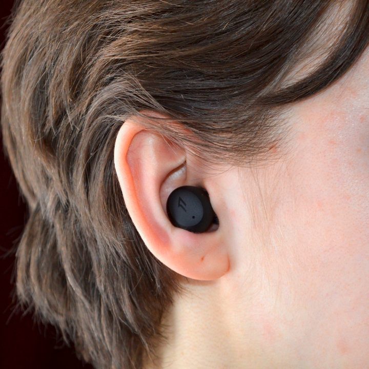 A woman wears the 1More ComfoBuds Mini earbuds.